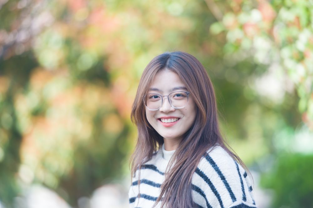 A young adult woman in a striped sweater smiling outdoors